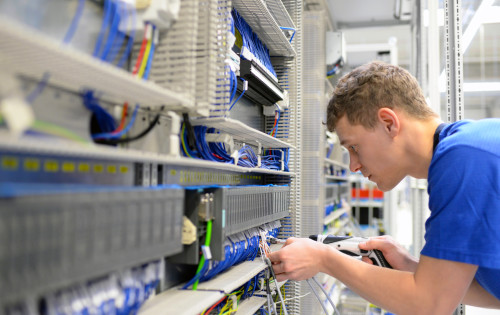 Elektroniker montiert Schaltschrank in der Industrie